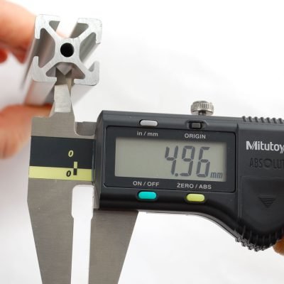 Quality assurance inspector measuring a custom machined brass component with a calibrated vernier caliper to verify strict dimensional tolerances.